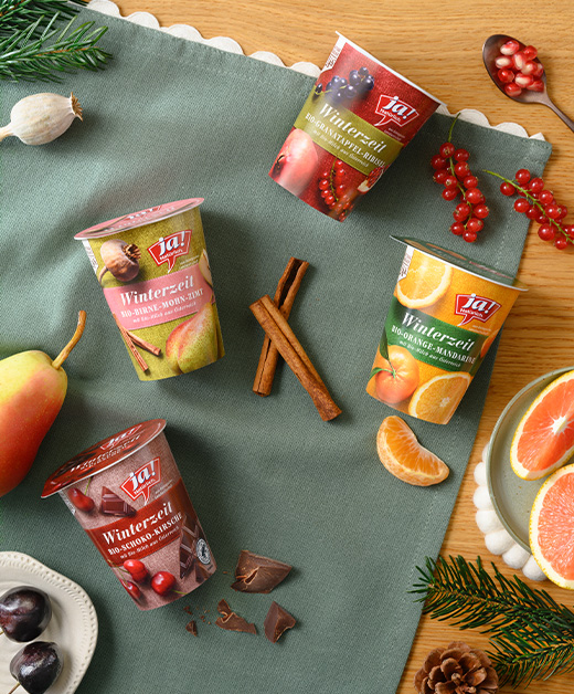 Winterzeitjoghurts aufgereiht mit frischen Früchten und Joghurt im Glas auf einem Tisch