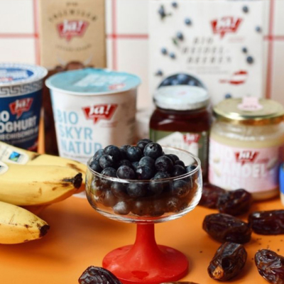 Bio-Zutaten für den Blueberry Almond Protein Lassi nebeneinander- im Vordergrund ein Glas mit Bio-Heidelbeeren.