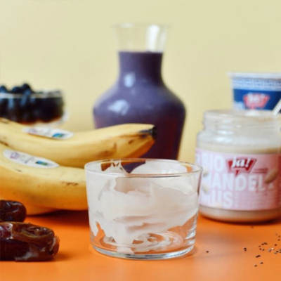 Ein Glas wird mit Bio-Mandelmus am inneren Glasrand bestrichen.