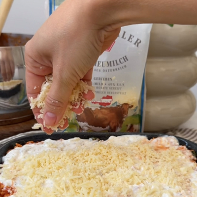 Als letzte Schicht der High Protein Lasagne wird geriebener Bio-Emmentaler in die Auflaufform gegeben.