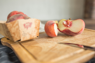 Geschnittene Bio-Plattpfirsiche von Ja! Natürlich auf einem Schneidebrett.