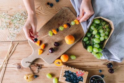 Jemand steckt Ja! Natürlich Bio-Heidelbeeren, Weintrauben und Marillen auf einen Spieß.