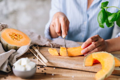 Jemand schneidet eine Bio-Melone.