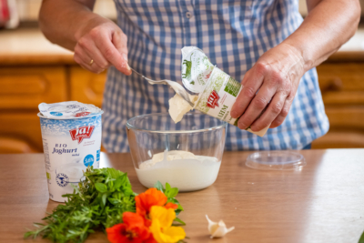 Jemand mixt Ja! Natürlich Bio-Sauerrahm und Joghurt in einer Schale.