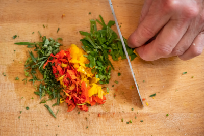 Jemand schneidet Bio-Gemüse und Schnittlauch.