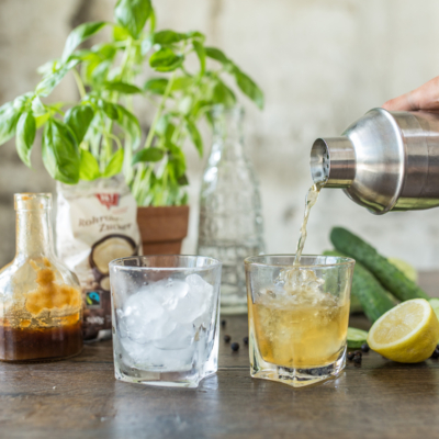 Jemand leert Gurken-Gin-Cocktail in Gläser mit Eis.