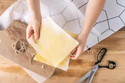Jemand hält Ja! Natürlich Bio-Wachstücher mit einer Schere daneben.