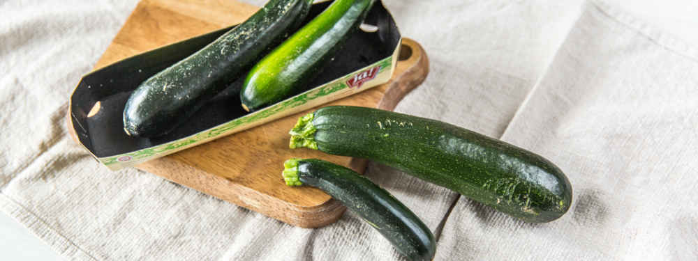 Ein Karton Ja! Natürlich Bio-Zucchini auf einem Brett.