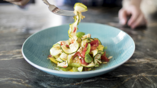 Jemand hält eine Gabel mit Bio-Zucchini-Raritäten-Pasta.