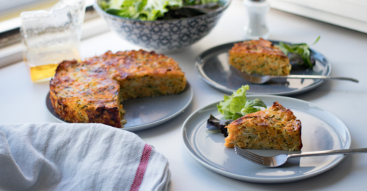Zucchinikuchen auf einem Teller, daneben zwei Teller mit jeweils einem Stück.