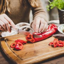 Jemand schneidet eine Bio-Paprika.