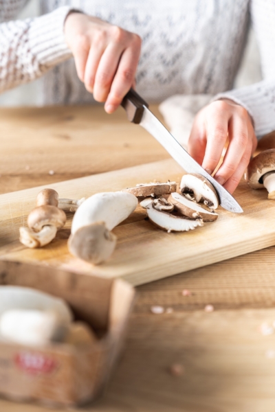 Jemand schneidet Bio-Champignons.