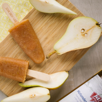 Birnen-Eis am Stiel mit geschnittenen Bio-Birnen auf einem Holzbrett.