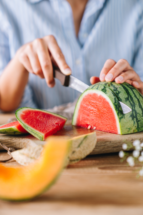 Jemand schneidet eine Bio-Wassermelone in Scheiben.