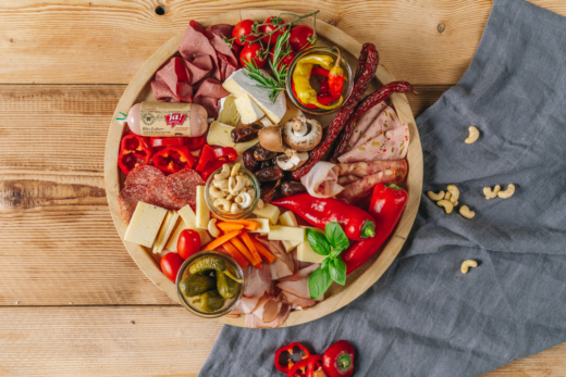 Verschiedene Wurst- und Käsesorten auf einem Brett angerichtet.