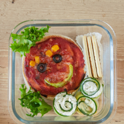 Bio-Minipizza für Kinder mit Gesicht aus Gemüse.