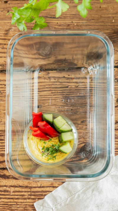 Eine Glasschale mit Gemüsesticks in Bio-Hummus.