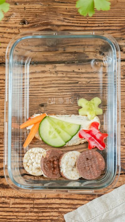 Ein Butterbrot mit Bio-Gemüse und Mini Schoko-Reiswaffeln in einer Glasschale.