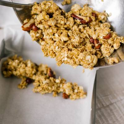 Jemand schüttet die Granolariegel-Masse in eine Form mit Backpapier.