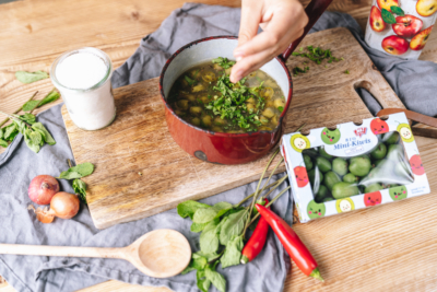 Jemand gibt geschnittene Bio-Minzblätter in den Topf.