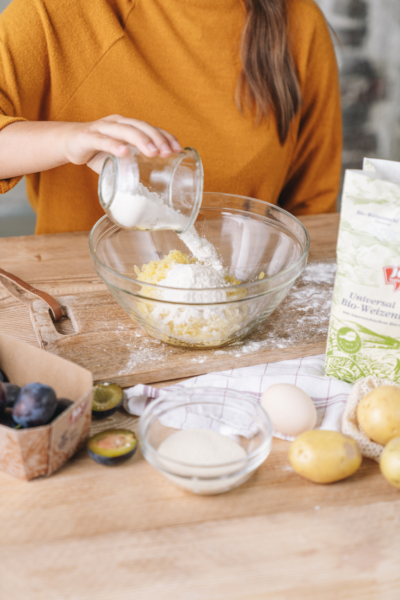 Jemand gibt Ja! Natürlich Bio-Weizenmehl in eine Schüssel.