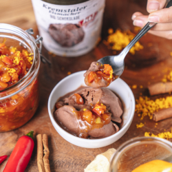 Jemand nimmt einen Löffel Bio-Kürbis-Orangen-Chutney aus einem Glas.