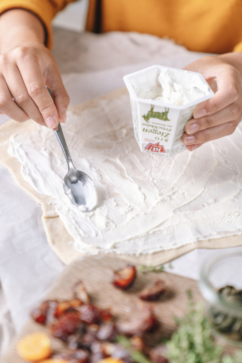 Jemand bestreicht Teig mit Ja! Natürlich Bio-Frischkäse.