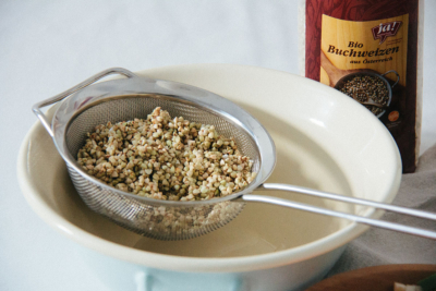 Ja! Natürlich Bio-Buchweizen wird in einem Sieb gewaschen.