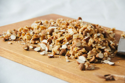 Gehackte Bio-Haselnüsse auf einem Holzbrett.