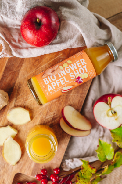 Eine Flasche Ja! Natürlich Bio-Ingwer-Apfel Shots auf einem Schneidebrett.