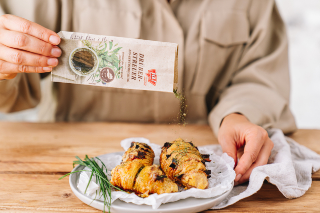 Jemand würzt ein Gericht mit der Ja! Natürlich Drüberstreuer Bio-Gewürzmischung.