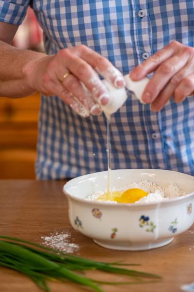 Jemand schlägt Bio-Eier in eine Schüssel mit Mehl auf.