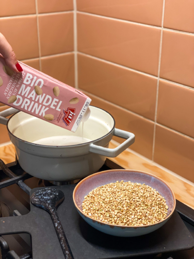 Jemand gießt Ja! Natürlich Bio-Mandeldrink in einen Topf auf dem Herd.