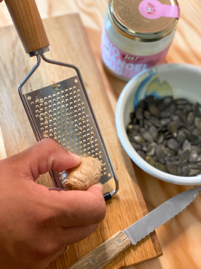 Jemand reibt Bio-Ingwer an einer Reibe.