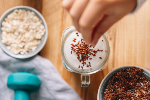 Jemand bestreut seinen Bio-Skyr mit Flohsamen.