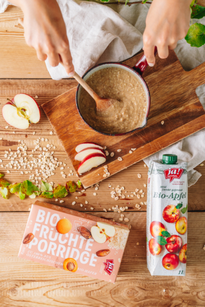 Jemand bereitet Ja! Natürlich Bio-Früchte-Porridge mit Apfelsaft zu.