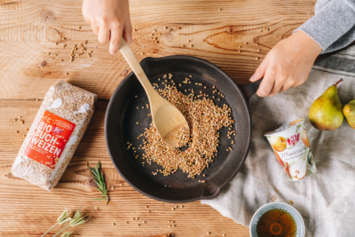 Jemand röstet Ja! Natürlich Bio-Buchweizen in einer Pfanne an.