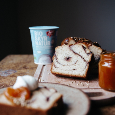 Babka mit Ja! Natürlich Bio-Skyr, Nougatcreme und Buchweizen, garniert mit süßer Kürbis-Apfelmarmelade auf einem Tisch.