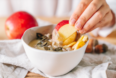 Jemand taucht eine Apfelspalte in ein Bio-Fruchtmus.