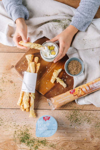 Jemand tunkt Stangerl aus Ja! Natürlich Bio-Dinkelblätterteig in einen Skyr-Dip.