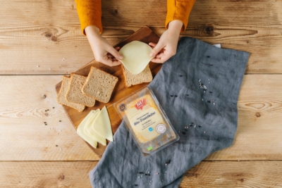 Jemand belegt Toast mit einer Scheibe Ja! Natürlich Bio-Käse.