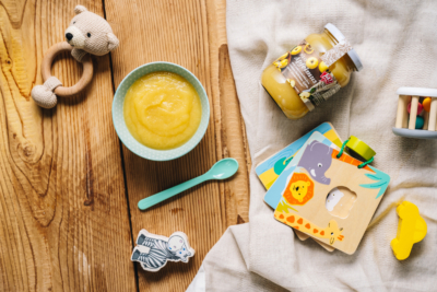 Eine Kinderschüssel mit Ja! Natürlich Bio-Apfelmus und Kinderspielzeug.