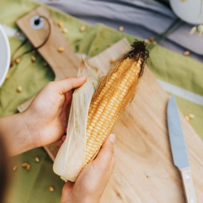 Jemand schält einen Bio-Maiskolben.