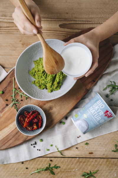 Jemand gibt Ja! Natürlich Bio-Skyr in eine Schüssel.