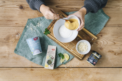 Jemand bereitet den Dip in einer Schüssel vor.