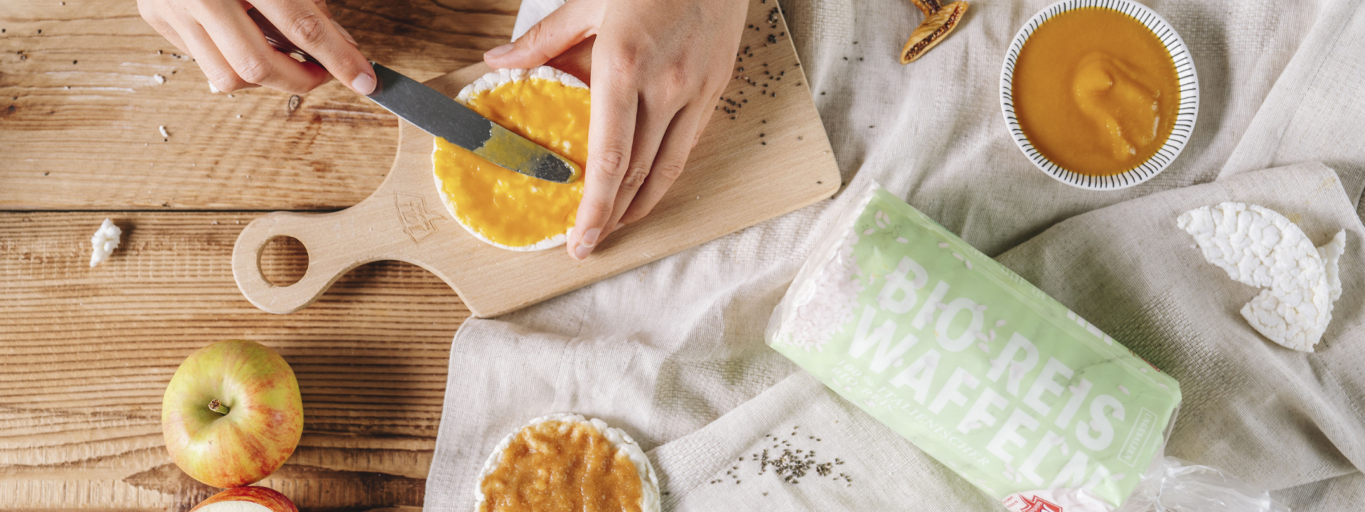 Jemand streicht Fruchtmus auf Ja! Natürlich Bio-Reiswaffeln.