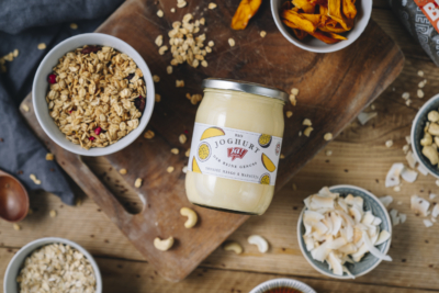 Ein Glas Ja! Natürlich Bio-Früchte-Joghurt auf einem Tisch mit Müsli.