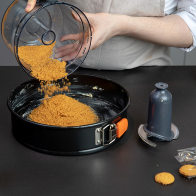 Jemand schüttet gemahlene Bio-Kekse in eine Kuchenform.