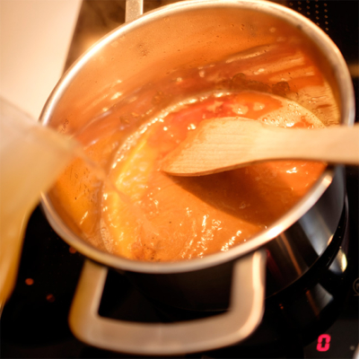 Bio-Saft und Wasser werden in einen Topf gegossen.