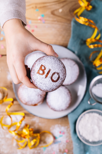 Jemand hält einen Bio-Krapfen mit der Aufschrift